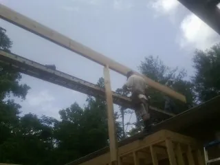 Carpenter setting a ridge beam over a new addition frame — Ice Dam Removal by Roofing Brothers in Inkster