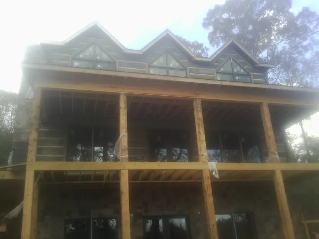 Dormers and porch framing on a large log home under construction — Roof Coating work by our crew in Inkster