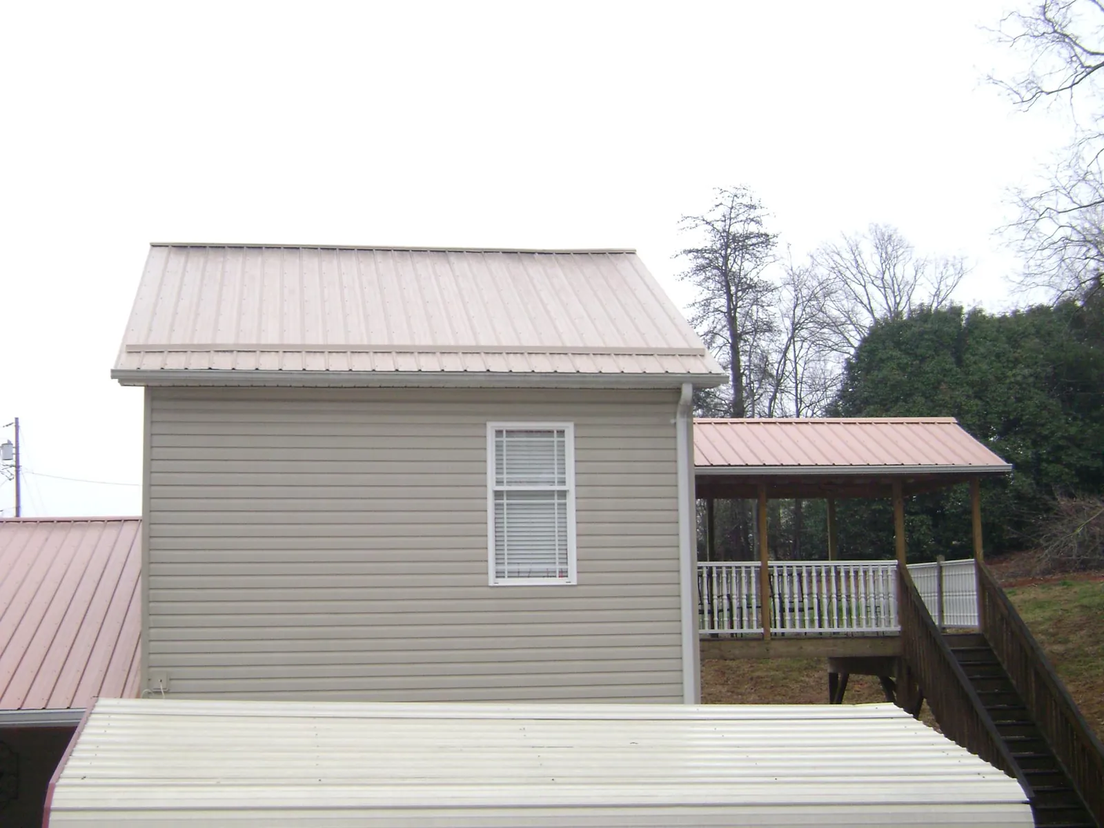 Tan metal roofs on a two story addition and attached porch, from a Roof Replacement job in Inkster
