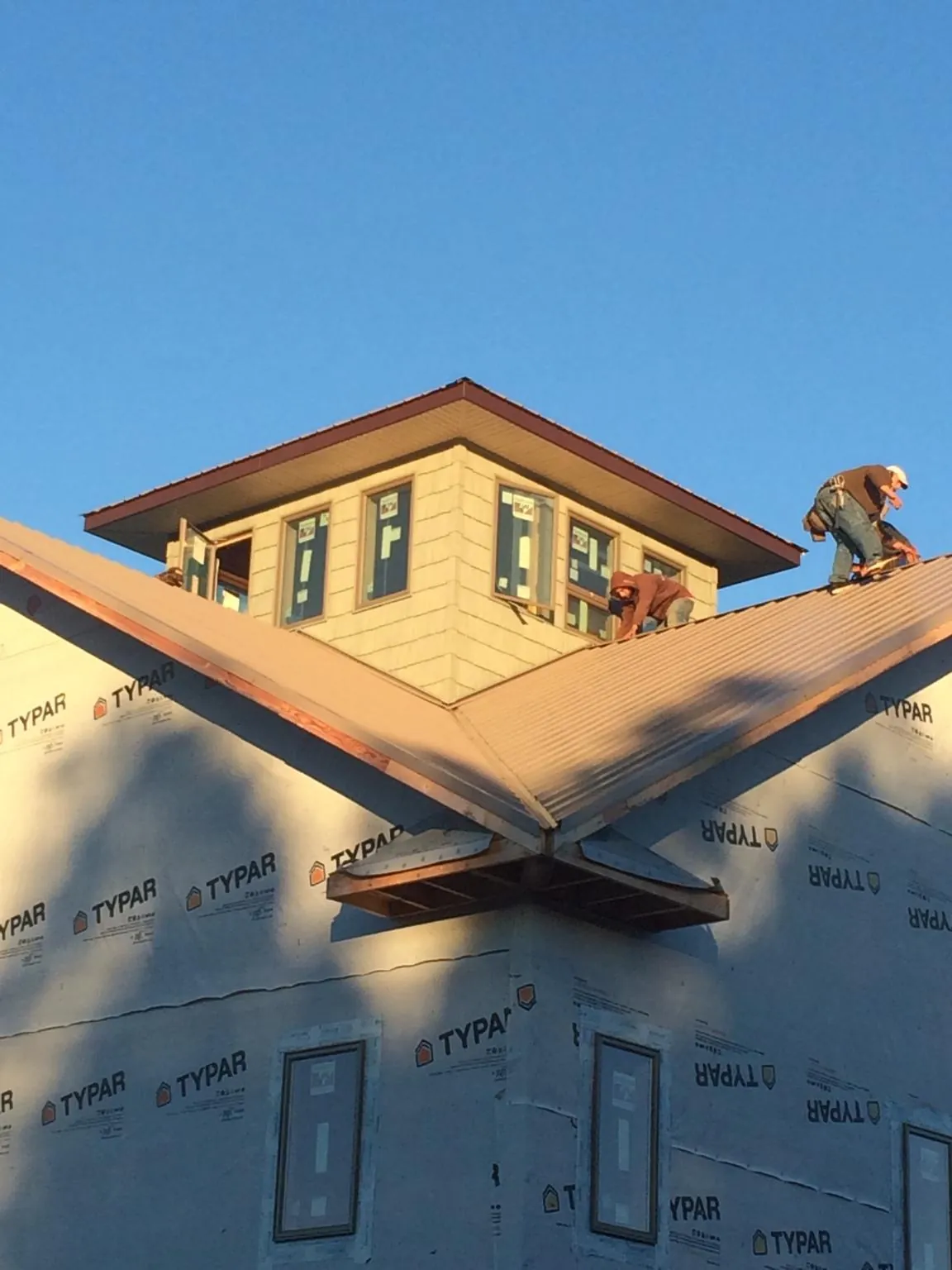Roofers working around a rooftop cupola on a new metal roof at sunset — Roof Waterproofing in Inkster by Roofing Brothers